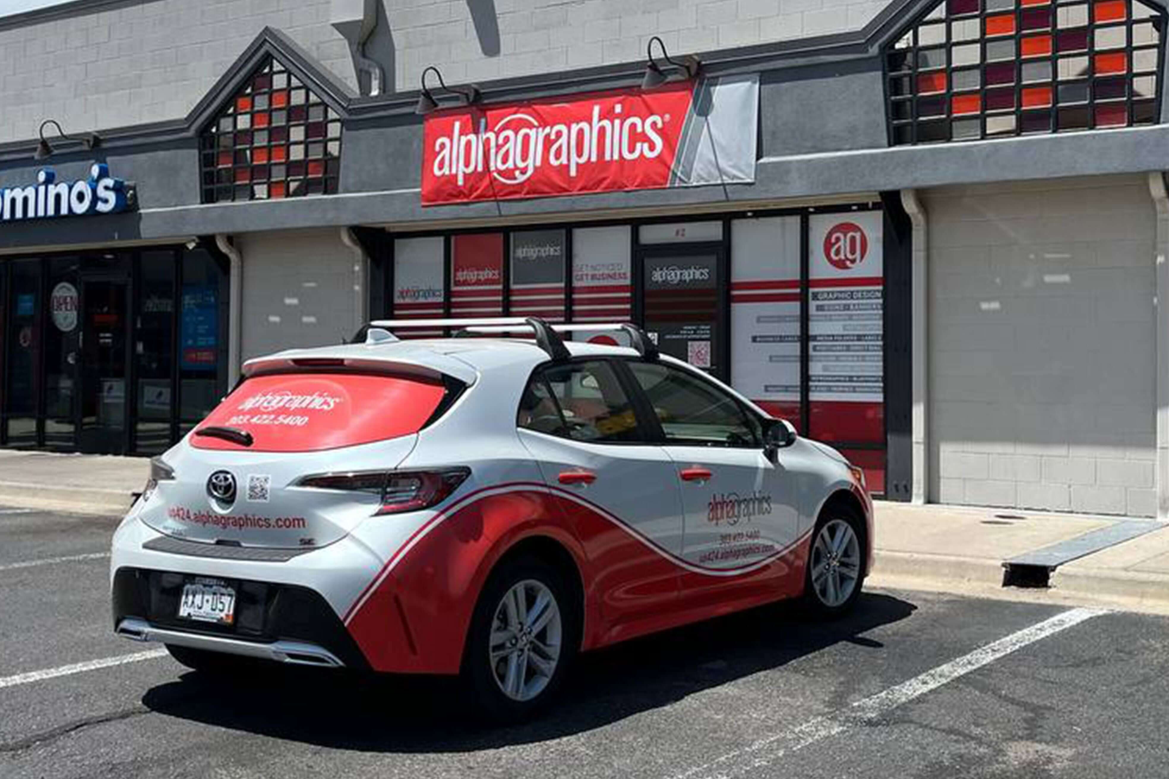 Front view of AlphaGraphics Aurora store with AG delivery car parked