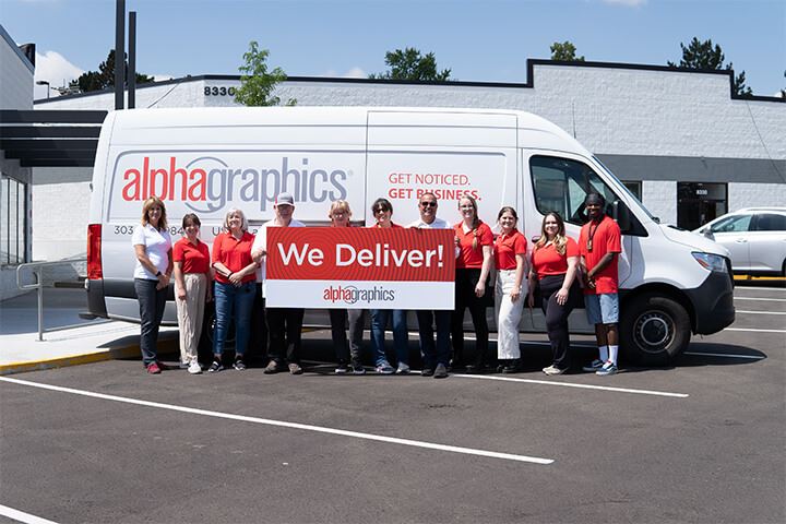 AlphaGraphics Arvada team smiling with delivery van and WE DELIVER signboard