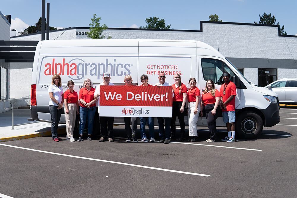 AlphaGraphics Arvada team smiling with delivery van and WE DELIVER signboard