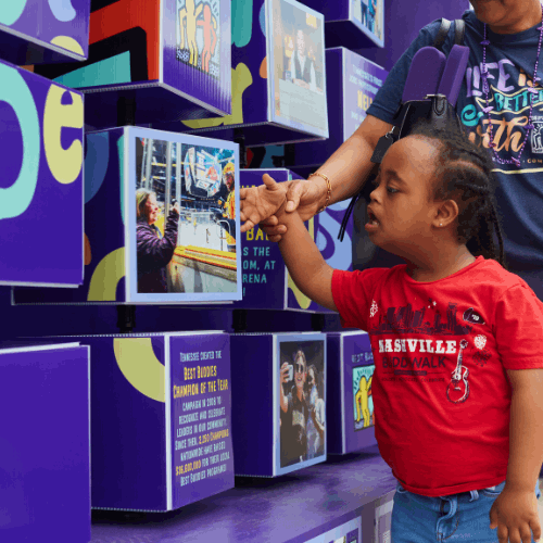 Young girl and woman spin cubes on a large interactive sign