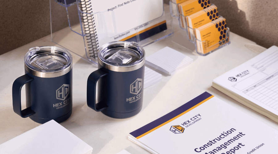 Promotional travel mugs sitting on a desk with printed marketing materials